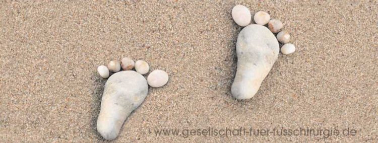 Zwei mit Steinen gelegte Fußabdrücke auf Sand
