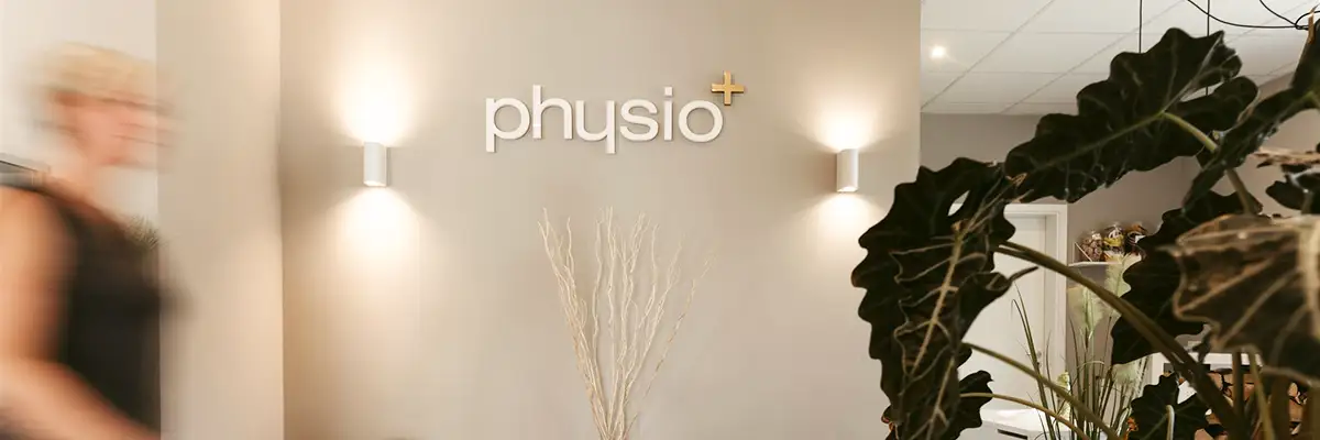 Wartebereich der Praxis mit dem physio+ Logo an der Wand